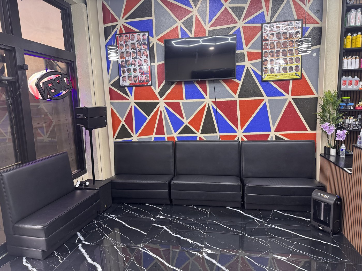Waiting lounge with black leather benches, a TV and a red, blue and grey geometric mural